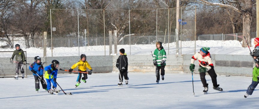 University of Ottawa students help children improve hockey skills on outdoor rink.